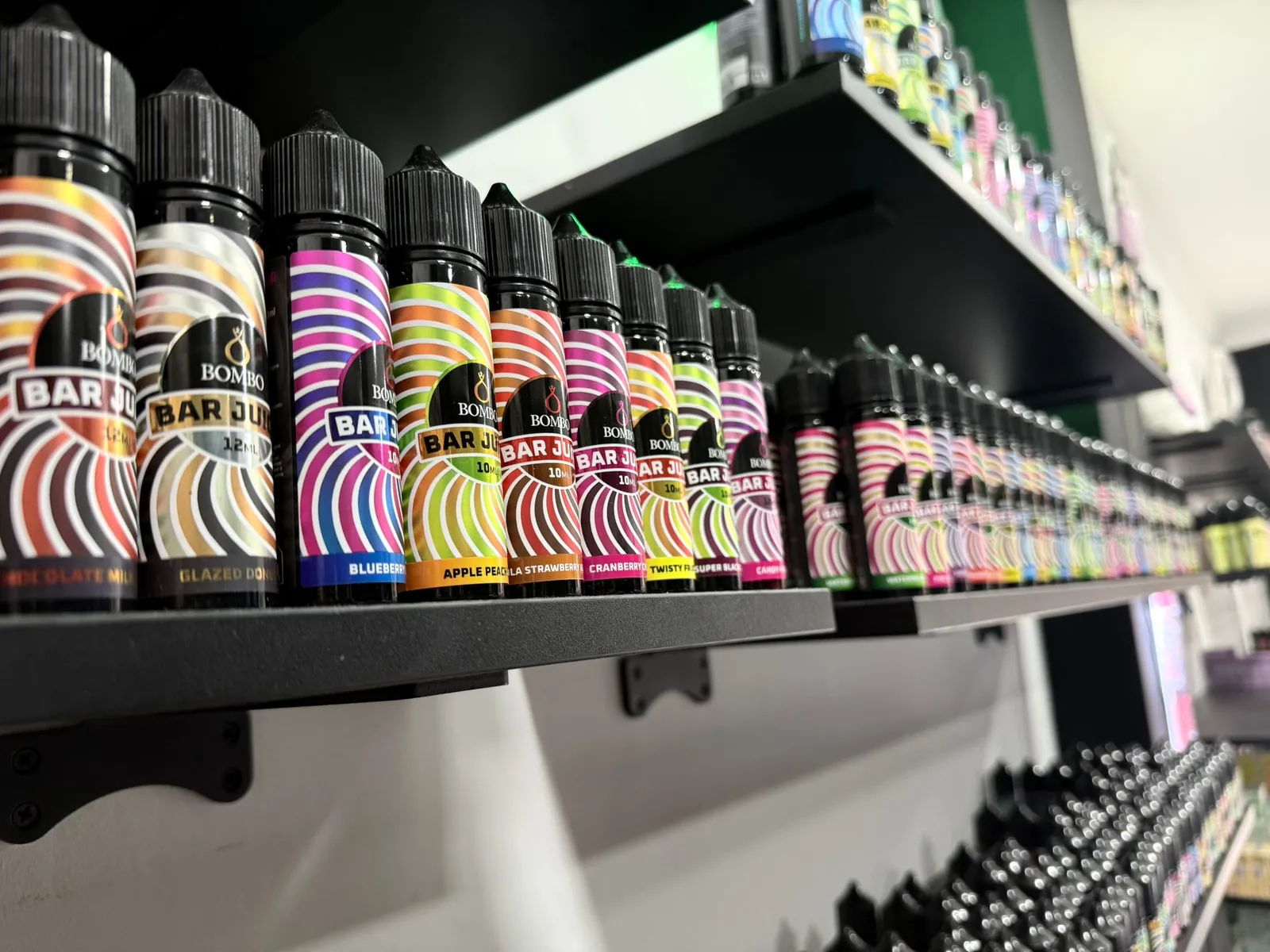 Baldas negras de MASVAPE en Málaga con filas de botellas de líquido de muchos colores